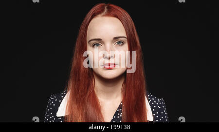 Porträt einer Frau mit langen rotbraunen Haaren auf schwarzem Hintergrund isoliert. Nahaufnahme einer Frau an Kamera schaut. Stockfoto