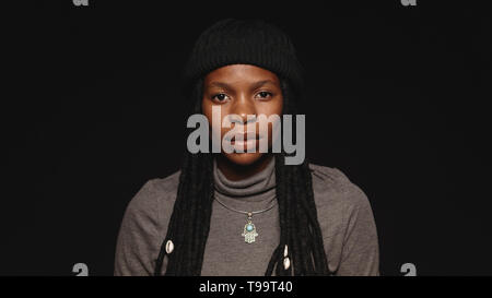 Portrait der afrikanischen Frau in T-shirt mit langen Dreadlocks. Porträt der afrikanischen Frau auf schwarzem Hintergrund isoliert. Stockfoto