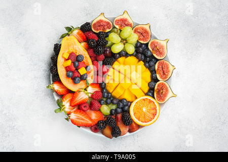 Leckere Obstplatte mango papaya Feigen orangen Beeren auf runder Servierteller auf weißem Hintergrund, Ansicht von oben, selektiver Fokus, kopieren Raum Stockfoto