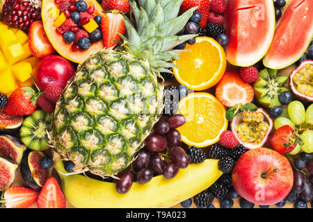 Köstliche Frucht Hintergrund mango Ananas Papaya Granatapfel Himbeeren orangen Beeren, selektiver Fokus, Ansicht von oben Stockfoto