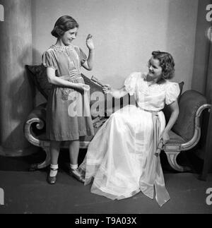 Eine klassische Pose von zwei Mädchen mit Knallbonbons posiert auf einer Chaiselongue c 1935 Foto von Tony Henshaw Stockfoto