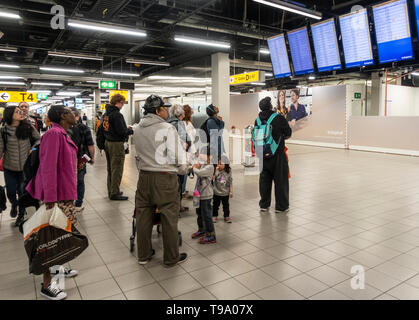 Passagiere Kontrolle der Anzeigetafel am Flughafen Schiphol, Amsterdam, Niederlande. Reisende, Passagiere, Reisen. Stockfoto