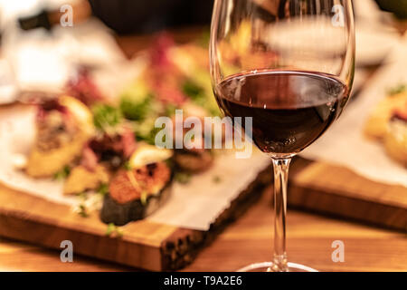Rotwein Gläser auf einem Holzbrett mit Defokussierten Antipasto catering Plattenteller im Hintergrund Stockfoto