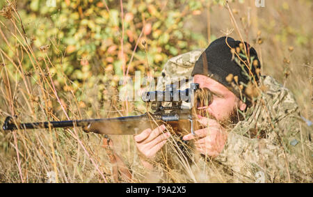 Mann Jäger mit Gewehr Pistole. Boot Camp. Uniform Mode. Bärtiger Mann Jäger. Die Streitkräfte. Camouflage. Jagd Fähigkeiten und Waffen Ausrüstung. Wie Jagd in Hobby. Wüste Schlachtfeld Stockfoto