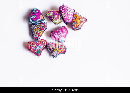Adorable kleine Herzen gestricken von Hand. Mit einem Thread von einer dicken sperrige Wolle Garn. bunte Tribal Style Symbol von Liebe Hintergrund Stockfoto