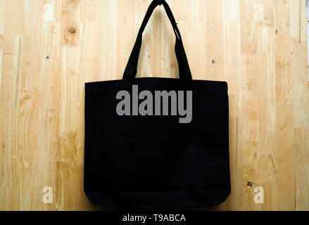 Schwarze Stofftasche auf Holz- Hintergrund. Leer, wiederverwendbare Tasche. Flach Stockfoto