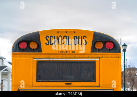In der Nähe der Rückseite eines gelben Schulbus gegen Wohnungen und bewölkter Himmel Stockfoto