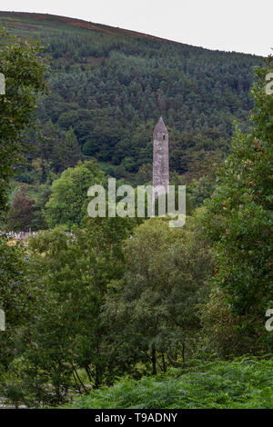Das Glendalough roundtower gesehen durch Bäume, Glendalough, County Wicklow, Irland. Stockfoto