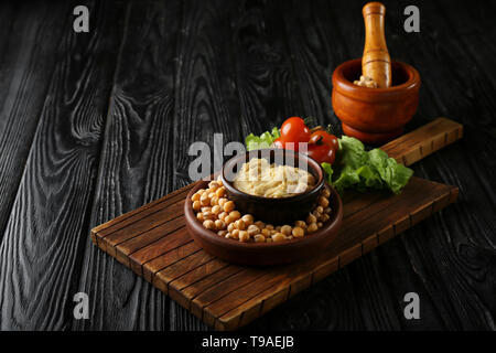 Lecker Hummus und Kichererbsen auf dunklen Holztisch Stockfoto