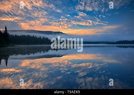 Nebel und Reflexion über Lac La Joie bei Sonnenaufgang Parc National du Mont Tremblant Quebec Kanada Stockfoto
