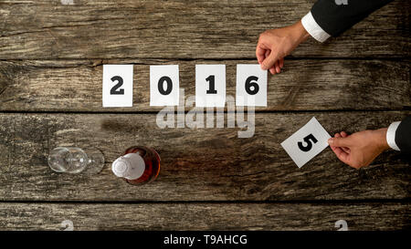 Geschäftsmann feiert Jahr 2015 rechnet kommt im Jahr 2016 als ändert er Nummer 5 für Nummer 6 auf 2016 Datum auf Papiere auf rustikalen hölzernen Schreibtisch liegen Stockfoto