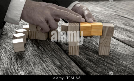 Nahaufnahme der Geschäftsmann bilden eine Brücke des kleinen Holzklötzchen in Graustufenbild mit zwei mittlere Würfel verbinden die beiden Seiten im stehen, im vi Stockfoto