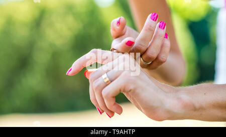 Nahaufnahme der gefleckte Marienkäfer krabbeln auf weibliche Hände mit lebhaften rosa Maniküre. Stockfoto