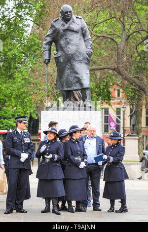 Westminster, London, UK, 17. Mai 2019. Winston Churchill's Statue auf den Parliament Square erscheint Blick auf eine Gruppe von Teilnehmern, die Links der nahe gelegenen früheren besonderen Service der Thanksgiving am Westminster Abbey zu markieren 100 Jahre Frauen Polizisten in der Met. Credit: Imageplotter/Alamy leben Nachrichten Stockfoto