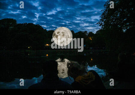 Brighton UK 17. Apr 2019 - Massen um Queens Park Teich in Brighton versammelten sich an diesem Abend das Brighton Festival Veranstaltung 'Museum der Mond' des Künstlers Luke Jerram, die zum 50. Jahrestag der Mondlandung gefeiert zu beobachten. Der Mond beleuchtet, über das Wochenende werden, begleitet von Musik des Komponisten Dan Jones. Foto: Simon Dack/Alamy leben Nachrichten Stockfoto