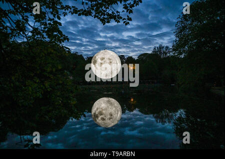 Brighton UK 17. Apr 2019 - Massen um Queens Park Teich in Brighton versammelten sich an diesem Abend das Brighton Festival Veranstaltung 'Museum der Mond' des Künstlers Luke Jerram, die zum 50. Jahrestag der Mondlandung gefeiert zu beobachten. Der Mond beleuchtet, über das Wochenende werden, begleitet von Musik des Komponisten Dan Jones. Foto: Simon Dack/Alamy leben Nachrichten Stockfoto