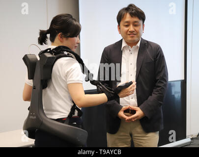 Tokio, Japan. 17 Mai, 2019. Japanese electronics Giant's Panasonic Roboter venture ATOUN Mitarbeiter ihre Servolenkung Anzug Powered mit neu Armteile unterstützt, was dabei hilft, einen schweren Gegenstand bei Panasonic des Büros in Tokio am Freitag, 17. Mai 2019, während ATOUN Präsident Hiromichi Fujimoto (R) Lächeln entwickelt Verschleiß zeigt. ATOUN entwickelt Powered Verschleiß im letzten Jahr des Benutzers zurück schwere Objekt für die Arbeiter der Lieferung, an Flughäfen, auf Baustellen und in der Landwirtschaft zu unterstützen. Credit: Yoshio Tsunoda/LBA/Alamy leben Nachrichten Stockfoto