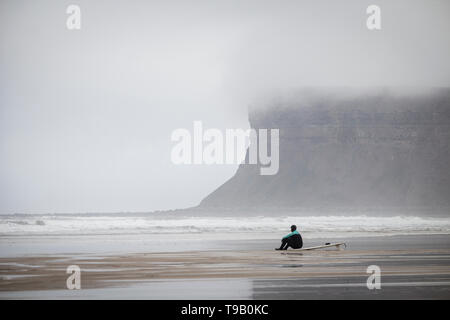 Surfer unter Nebel gehüllt Klippen an saltburn am Meer, North Yorkshire, England. Großbritannien Stockfoto