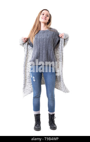 Glückliche junge Frau in warmen Winter Kleidung aus Gewirken Ausbau lange Strickjacke lächelnd und weg schauen. Voller Körper auf weißem Hintergrund. Stockfoto