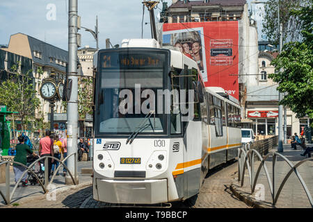 Eine dreigeteilte Straßenbahn, die Route 21, in Piata Sf Georghe (St George Square) im Stadtgebiet Der Altstadt von Bukarest, Rumänien. Menschen gehen und entspannen Stockfoto