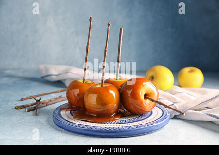 Leckeres karamel Äpfel mit Zweigen auf Platte Stockfoto