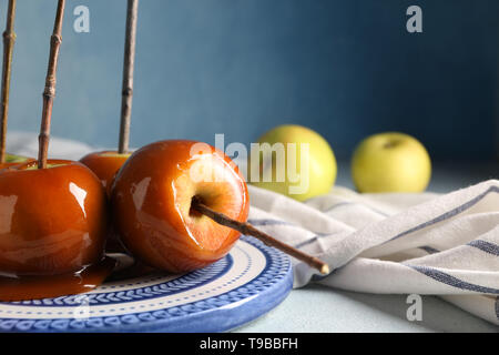 Leckeres karamel Äpfel mit Zweigen auf Platte Stockfoto