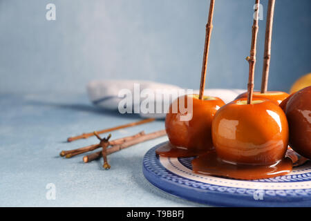 Leckeres karamel Äpfel mit Zweigen auf Platte Stockfoto