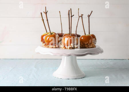 Leckeres karamel Äpfel mit Zweigen auf Stativ Stockfoto