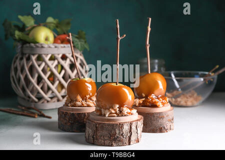 Leckeres karamel Äpfel mit Zweigen auf Holz steht Stockfoto