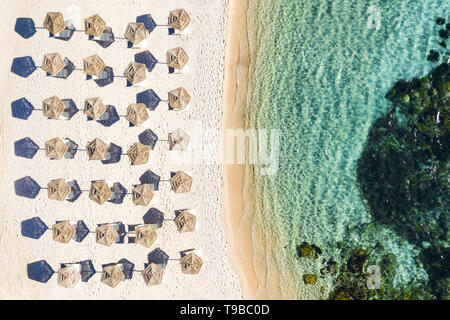 Ansicht von oben, einen atemberaubenden Blick auf einen weißen Strand mit Sonnenschirme für den Strand und das türkisfarbene Meer. Emerald Küste (Costa Smeralda, Sardinien, Italien. Stockfoto