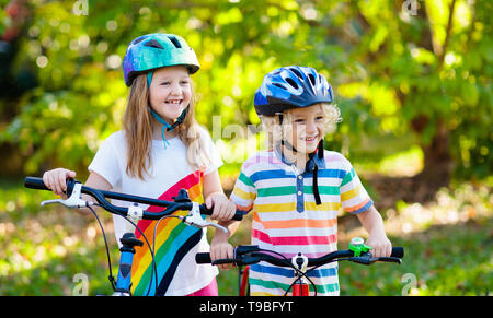 Kids on Bike im Park. Kinder in die Schule zu tragen sichere fahrradhelme. Kleine Jungen und Mädchen Radfahren auf sonnigen Sommertag. Aktiv gesund Outdoor sp Stockfoto