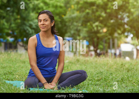 Ziemlich skinny sportliche junge Frau sitzen auf Yoga Matte in grün Sommer Park Hintergrund Stockfoto