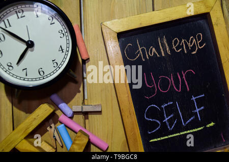 Stellen Sie sich der Herausforderung auf Phrase bunte handgeschrieben auf schiefertafel und Wecker mit Motivation, Inspiration und Bildung Konzepte. Tabelle Hintergrund Stockfoto
