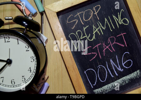 Hören Sie auf zu träumen anfangen, auf Phrase bunte handgeschrieben auf schiefertafel und Wecker mit Motivation, Inspiration und Bildung Konzepte. Tisch zurück Stockfoto