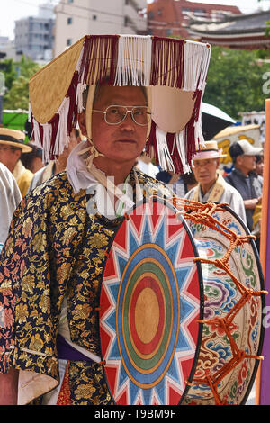 Japaner in Gläsern und einer einzigartigen Hut spielt eine traditionelle Trommel mit bunten Mustern während einer Prozession am Sanja Matsuri Festival in Tokio. Stockfoto