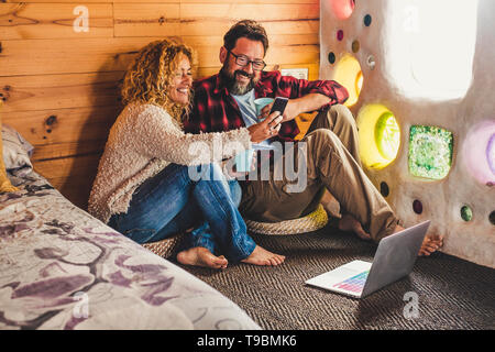 Glückliches Paar in Beziehung und Liebe zusammen Technologie für Arbeiten oder Spaß-alternative Menschen suchen Handy Display lächelnd und Havin Stockfoto