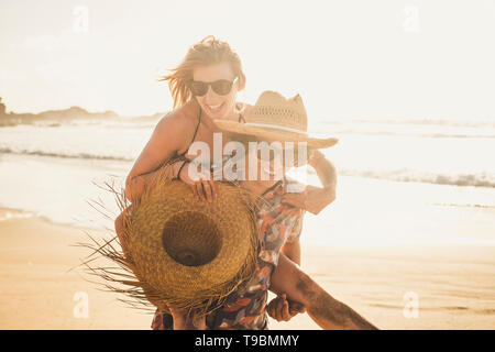 Junge fröhliche Menschen Spaß in Paar mit Mann tragen schöne Frau - gemeinsam lachen und genießen Sie die sonnigen Tag Urlaub Urlaub im Werden. Stockfoto