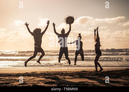 Sonnenuntergang am Strand mit glücklichen Gruppe von Jugendlichen springen Spaß haben - Freunde auf Sommerurlaub Urlaub zusammen genießen in Freundschaft - Sandy l Stockfoto
