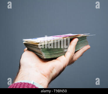 Mann hand Stapel Stapel Euro Dollar Währung tausende von Banknoten gegen grauer Hintergrund Stockfoto