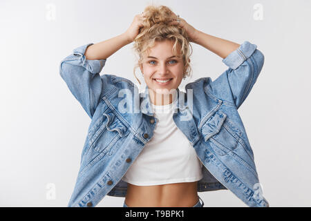 Charmant lächelnde blonde lockige blonde blauäugige Frau berühren Haar glücklich grinsend genießen Flauschige gesunde Haare Kosmetik empfehlen Stockfoto