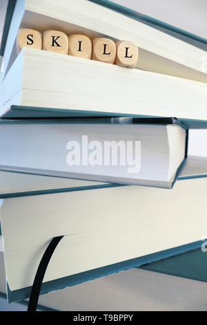 Skill Nachricht in Holzblöcke zwischen den Seiten eines Buches in einem Stapel von Büchern, Symbol geschrieben, Konzept Stockfoto