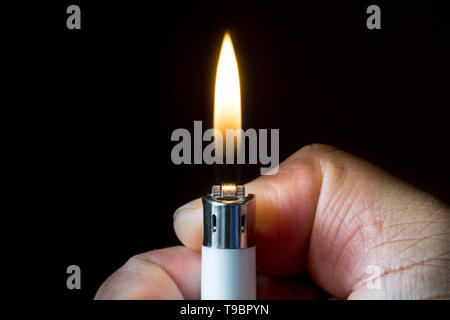 Eine Hand, eine mit Flamme und dunklen Hintergrund leichter. Stockfoto