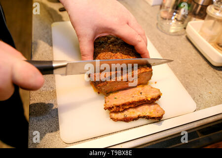 Frau Hände schneiden Stück Hackbraten, sie für die Verkostung der Lebensmittel in der Küche zubereiten. Koch schneiden Hackbraten mit Messer an Bord Restaurant Küche. Stockfoto