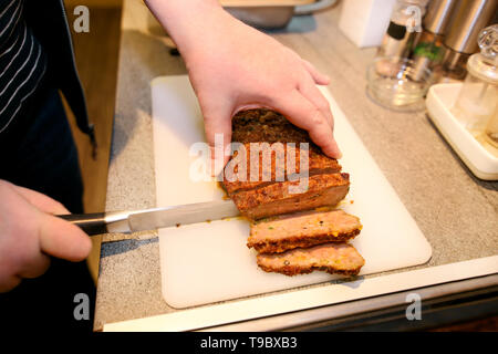 Frau Hände schneiden Stück Hackbraten, sie für die Verkostung der Lebensmittel in der Küche zubereiten. Koch schneiden Hackbraten mit Messer an Bord Restaurant Küche. Stockfoto