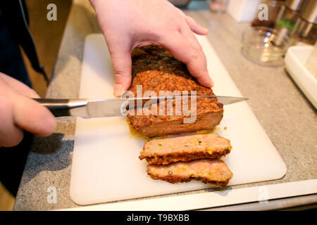 Frau Hände schneiden Stück Hackbraten, sie für die Verkostung der Lebensmittel in der Küche zubereiten. Koch schneiden Hackbraten mit Messer an Bord Restaurant Küche. Stockfoto