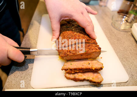 Frau Hände schneiden Stück Hackbraten, sie für die Verkostung der Lebensmittel in der Küche zubereiten. Koch schneiden Hackbraten mit Messer an Bord Restaurant Küche. Stockfoto