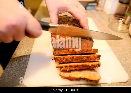 Frau Hände schneiden Stück Hackbraten, sie für die Verkostung der Lebensmittel in der Küche zubereiten. Koch schneiden Hackbraten mit Messer an Bord Restaurant Küche. Stockfoto