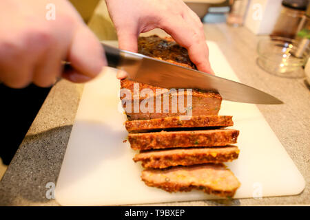 Frau Hände schneiden Stück Hackbraten, sie für die Verkostung der Lebensmittel in der Küche zubereiten. Koch schneiden Hackbraten mit Messer an Bord Restaurant Küche. Stockfoto