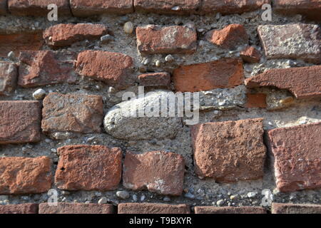 Nahaufnahme einer alten mittelalterlichen Mauer aus roten Ziegeln und Graue Steine unter Sonneneinstrahlung vorgenommen. Stockfoto