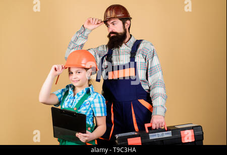 Vater und Tochter in der Werkstatt. Bärtiger Mann mit kleines Mädchen. Bauarbeiter assistant. Builder oder Tischler. Handwerker in Uniform. Ingenieur. Reparieren. Kinder Kreativität. Team bei der Arbeit. Stockfoto